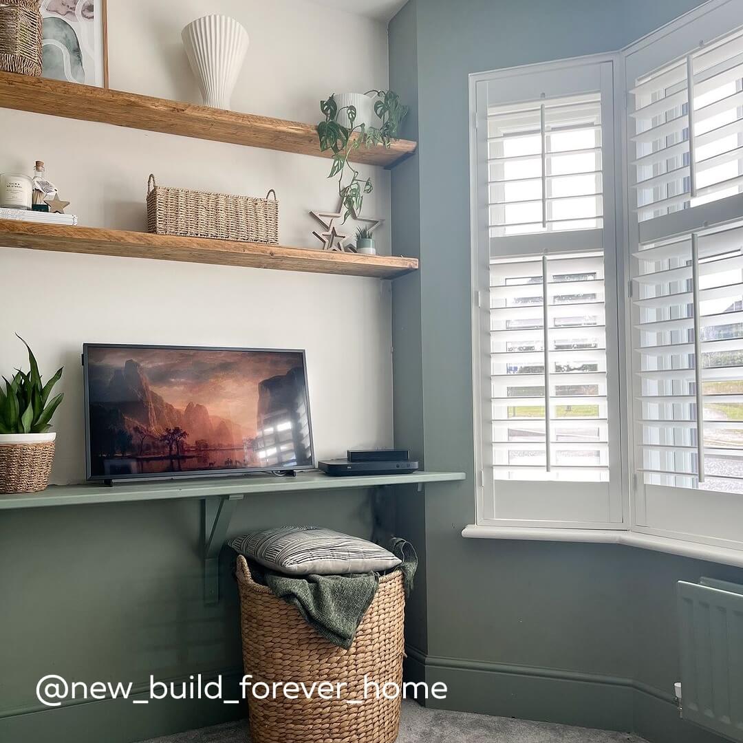 White Full Height Shutters with central tilt in a modern home with pale blue walls & wooden shelves