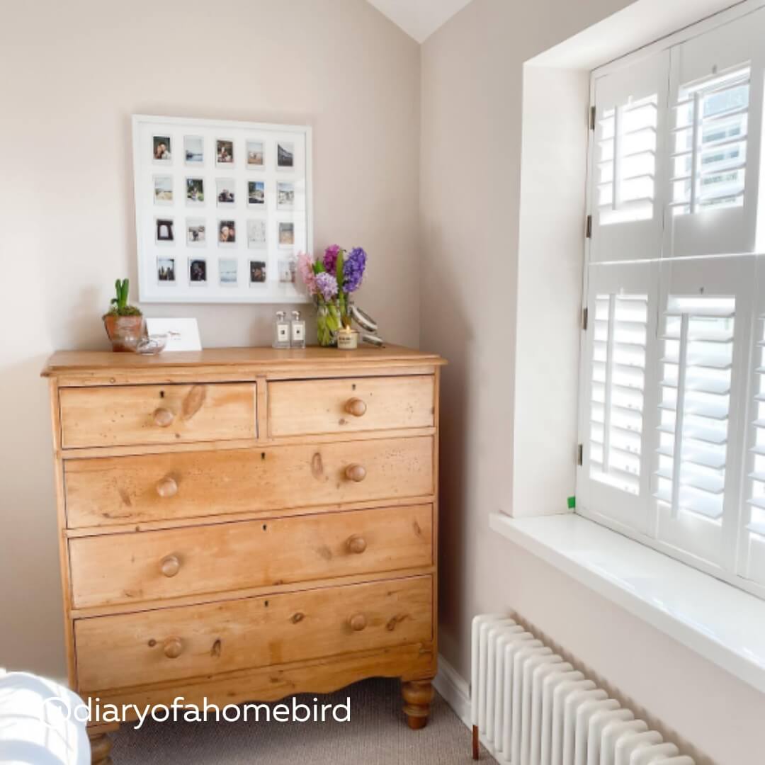 White Tier on Tier Shutters in a bright bedroom with wooden cupboard and hyacinths