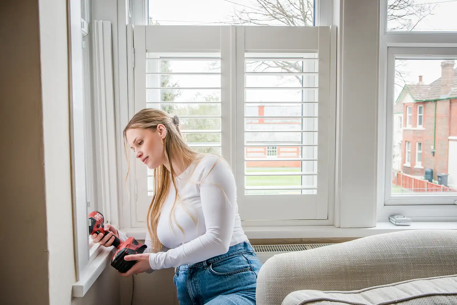 Woman DIY installing window shutter frame by drilling